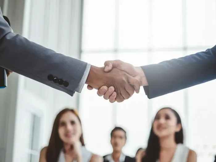 Closeup handshake between business professionals in a bright office, representing partnerships and listings